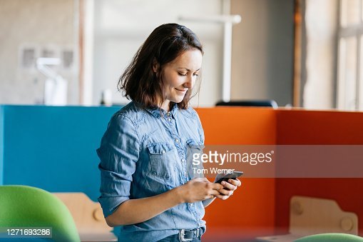 An office employee taking a break and using her smartphone to message friends.
