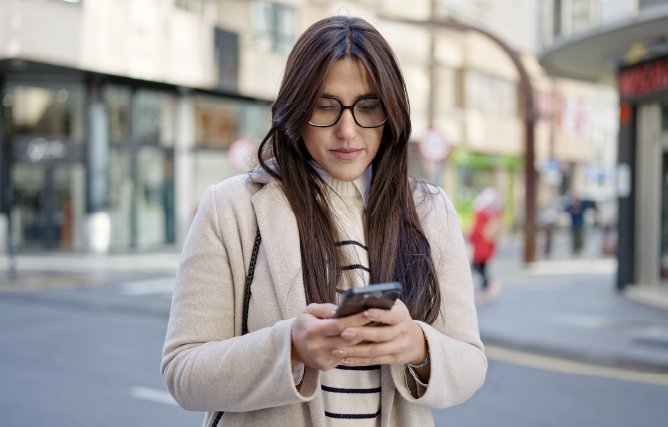 Woman looking at incoming text-to-donate messages on her phone. 