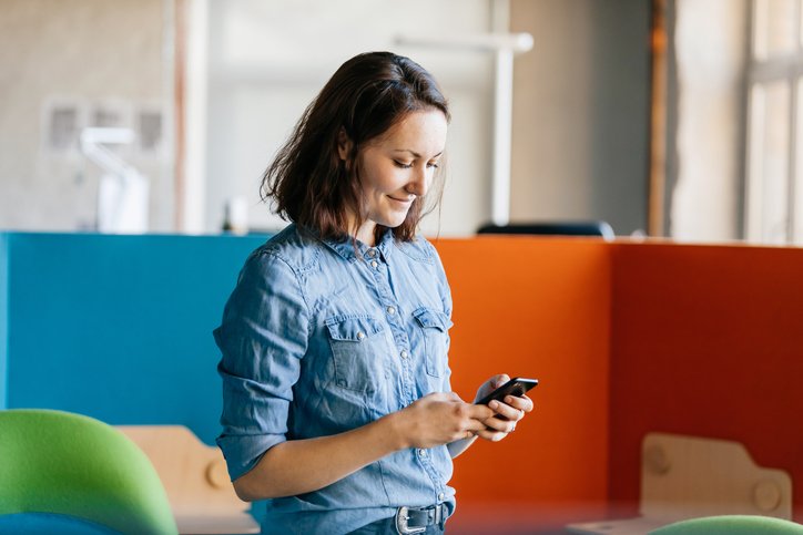 An office employee taking a break and using her smartphone to message friends.